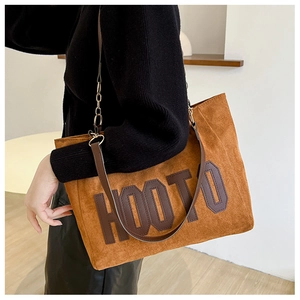 Close-up of brown suede tote bag with HOOTO leather lettering and chain strap details