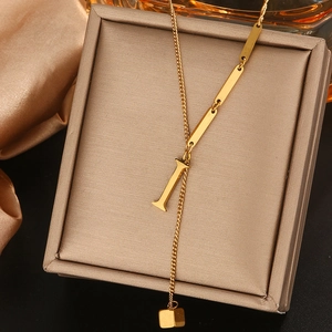 Detail van gouden titanium Lariat-ketting met letter I-hanger en rechthoekige kwastjes