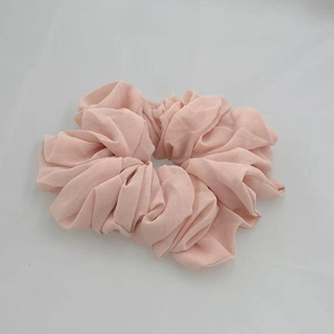 Macro shot of single light pink chiffon scrunchie showing soft pleated fabric texture