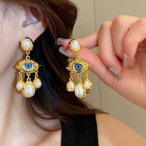 Detail of vintage evil eye earrings with blue center and three white teardrop pearls