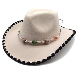Detail of cream western wool fedora featuring hand-stitched edging and bohemian beaded band