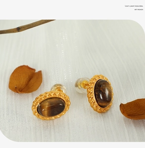 Detailed view of vintage oval tiger eye stone earrings with a twisted gold border