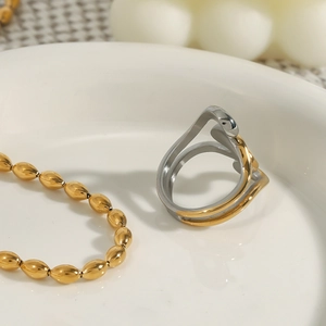 Dettaglio macro di anello bicolore oro e argento con catena di perle d'oliva lucida