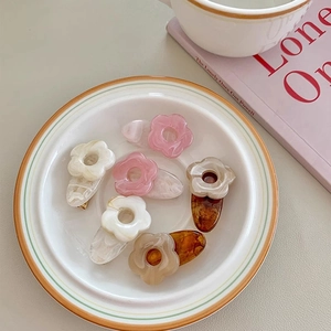 Minimalist flower hair clips in pink and white resin displayed on a ceramic plate