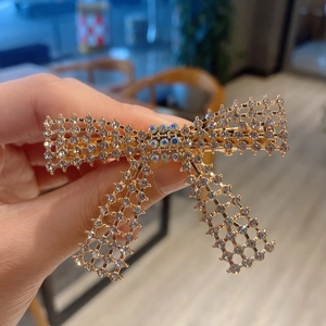 Detailed view of a gold bow hair clip set with sparkling white and iridescent rhinestones