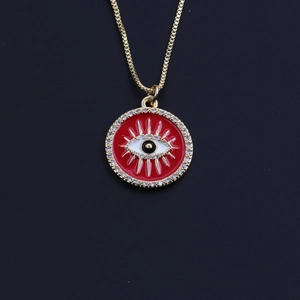 Macro detail of gold plated Evil Eye necklace with red enamel and sparkling crystals