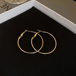 Gros plan de boucles d'oreilles créoles dorées sur velours noir en coffret