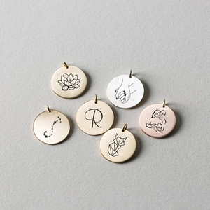 Detailed flat lay of stainless steel round pendants in gold, silver, and rose gold finishes