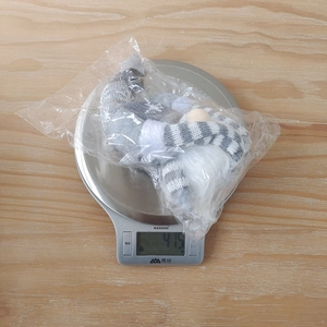Weight measurement of a knitted Christmas gnome plush doll on a digital scale