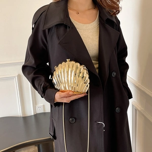 Golden shell-shaped acrylic evening clutch bag with chain strap shown on a model
