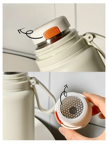 Detail of cream thermal bottle showing press-to-pour lid and stainless steel tea infuser