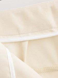 Macro view of interior waist stitching and white piping on beige twill trousers