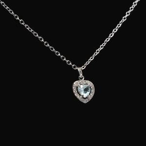 Macro view of heart-shaped light blue stone necklace with diamond halo on silver chain