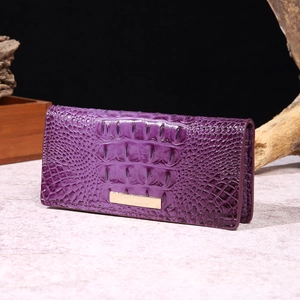 Detail of purple crocodile-embossed leather wallet with gold metal plate on marble