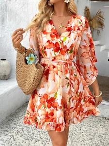 Detail of V-neck orange floral chiffon dress with ruffled hem and waist tie
