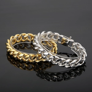 Close-up of polished gold and silver Cuban link bracelets on transparent stands