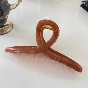 Macro view of a 15cm amber acrylic shark hair clip with a gold metallic spring