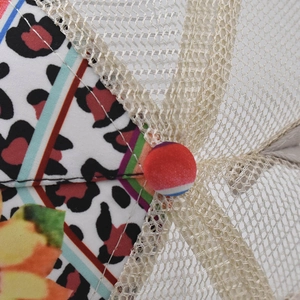Detail of leopard print fabric and breathable mesh with a red button on baseball cap