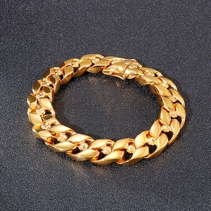 Detailed view of golden Cuban link bracelet with intricate skull relief on black background