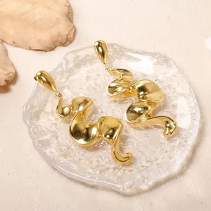 Boucles d'oreilles artistiques en acier inoxydable doré sur un plateau en verre