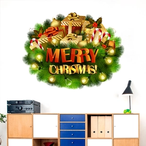 Golden Merry Christmas wall decal with gift boxes and pine needles on a white wall