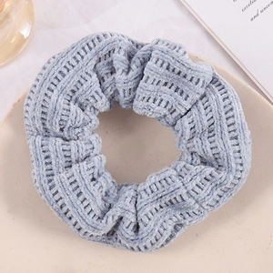 Blue knitted textured scrunchie for women shown on a beige ceramic plate in soft light
