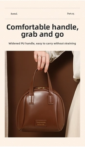 Detail of wide PU leather handle and gold zipper on large brown shell makeup bag