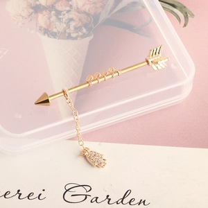 Detailed close-up of a golden arrow industrial bar with a hamsa hand charm and beads