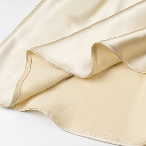 Detail of champagne satin dress showing fabric texture and high-quality hem stitching