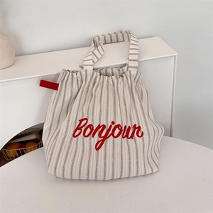 Detail of striped canvas tote bag featuring red Bonjour embroidery and drawstring closure