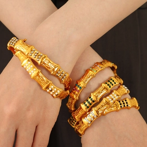 Bamboo style golden bangle with colorful gemstones and pearls shown on a model