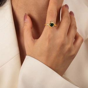 Elegante anello a corona d'oro con smeraldo verde a forma di cuore indossato su un abito