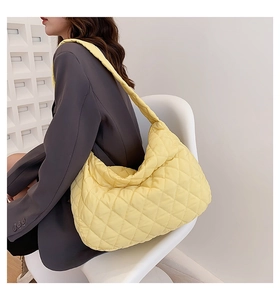 Detailed shoulder view of a large yellow quilted puffer dumpling bag on a model