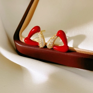 Vue macro détaillée de boucles d'oreilles nœud en émail rouge plaquées or 18k et zircon