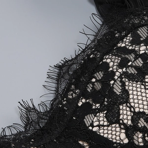 Detailed close-up of black eyelash lace fabric with intricate floral cutout patterns