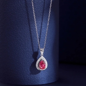 Detail of pear-cut magenta gemstone pendant with white micro-diamonds on silver chain