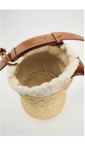 Top view of straw bucket bag with brown leather straps and beige canvas drawstring lining