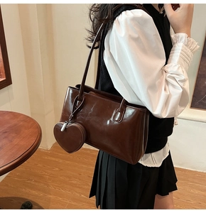 Detail of dark brown leather tote bag with heart-shaped coin purse on model in a cafe