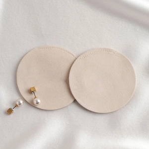 Detailed top view of round beige microfiber jewelry pouches on white silk background