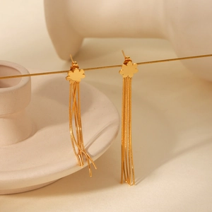 Detail of gold flower stud earrings with long tassel chains on artistic white decor