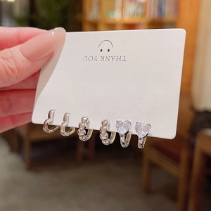 Three pairs of silver heart earrings with cat eye stones and cubic zirconia on a display card