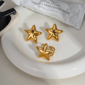 Golden star jewelry set with ring and earrings on a white plate in minimalist style