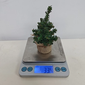 Close-up of 30cm mini burlap Christmas tree weighing 334 grams on a digital scale