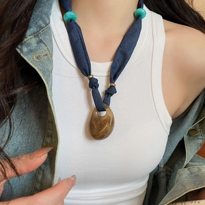 Detail of denim bow necklace with amber resin heart pendant and turquoise beads