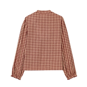 Detail view of red and beige small checkered pattern fabric on long sleeve shirt