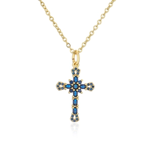 Macro detail of 18K gold-plated cross pendant with micro-set blue stones and reflection