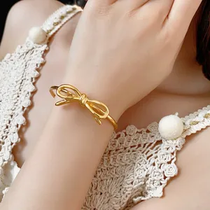 Bracciale rigido a fiocco placcato oro 18 carats lucido con design aperto indossato