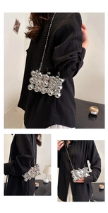 Macro view of silver metallic bead acrylic clutch bag with detachable chain strap detail