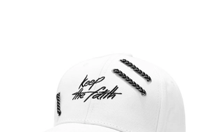 Detailed shot of white baseball cap with Keep the faith embroidery and woven rope accent