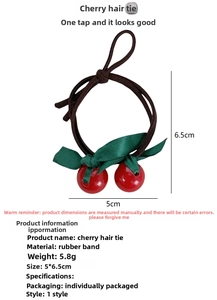 Close-up of elastic hair tie featuring red resin cherry charm and green ribbon leaf detail
